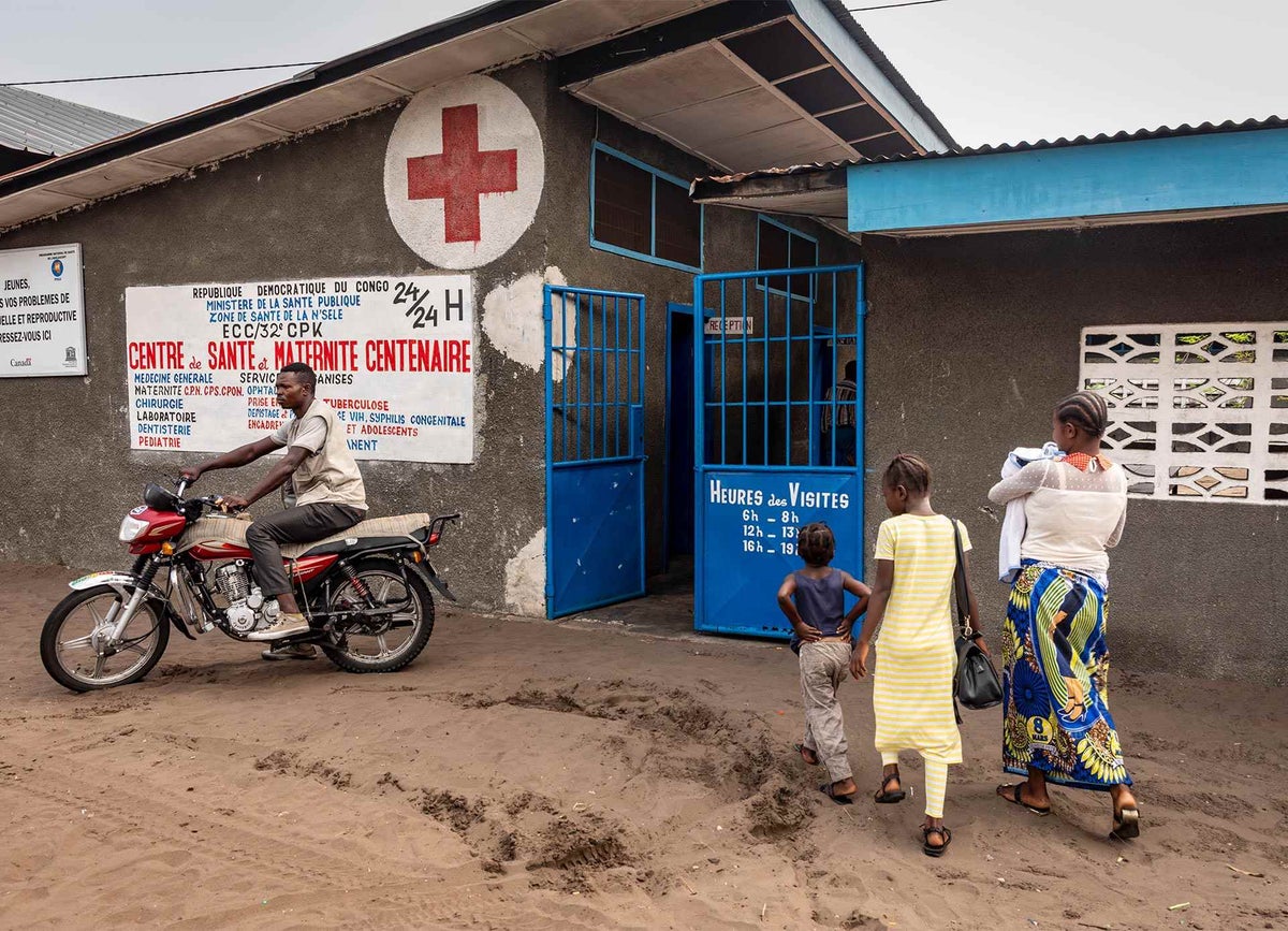 Mama Bwanga (right) and her three remaining children arrive at a health on the outskirts of Kinshasa, capital of the DRC, where the two youngest will receive measles vaccines. 