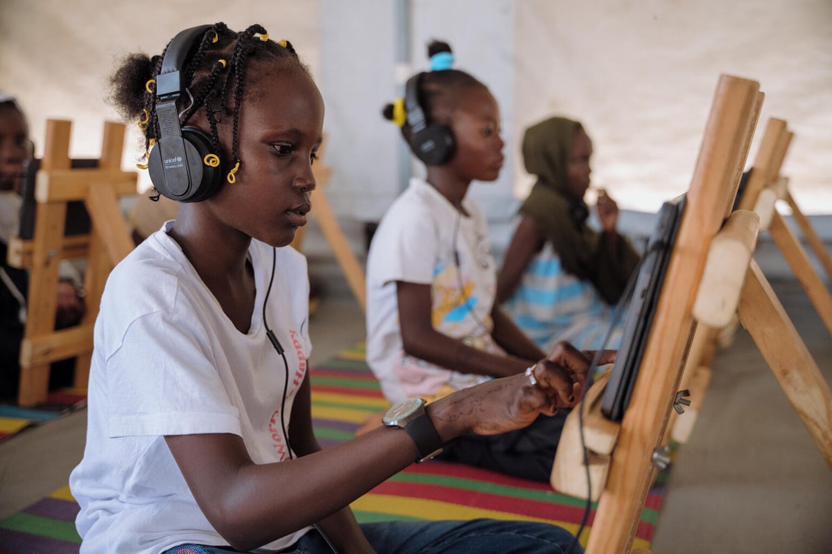 A girl uses a tablet for learning inside a tent.