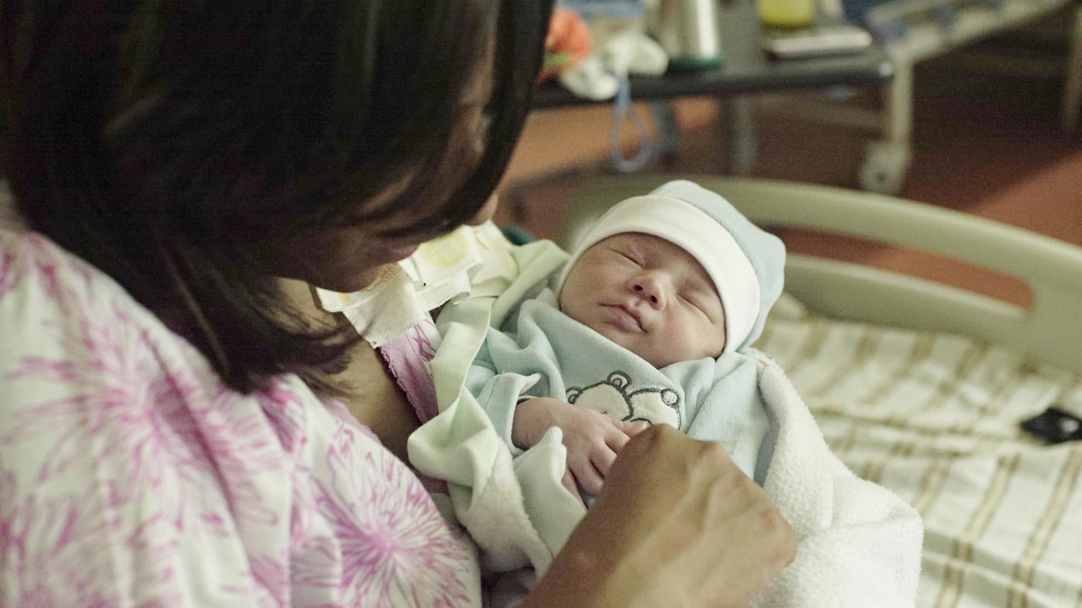 A newborn baby held by their mum.