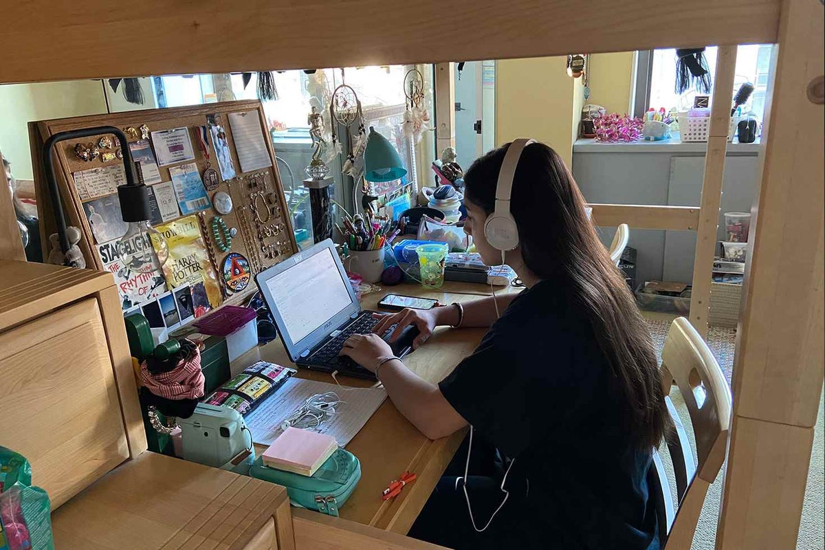 A teen attends online education. She has set up a dedicated work space at her home in New York. 