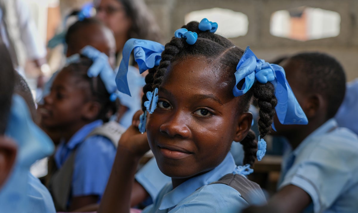 Child in school, wearing blue uniforms and ribbons.