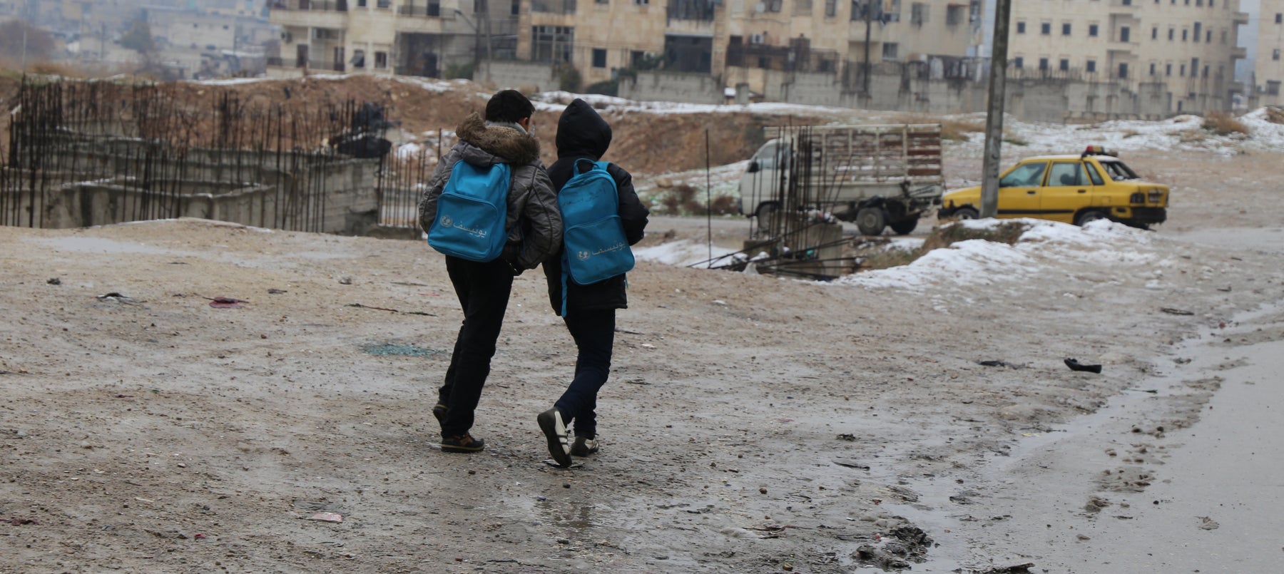 Children walking to school throw a street destroyed by conflict