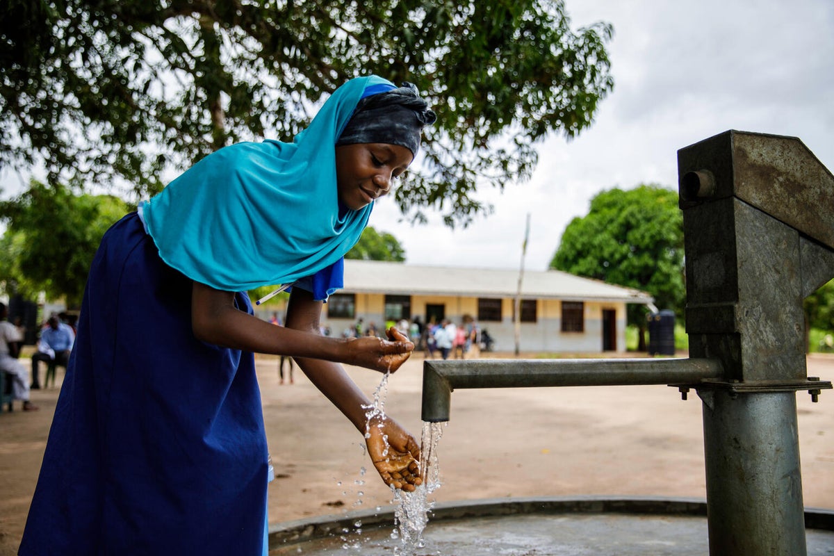 A teenage girl uses the school's new water facilities.