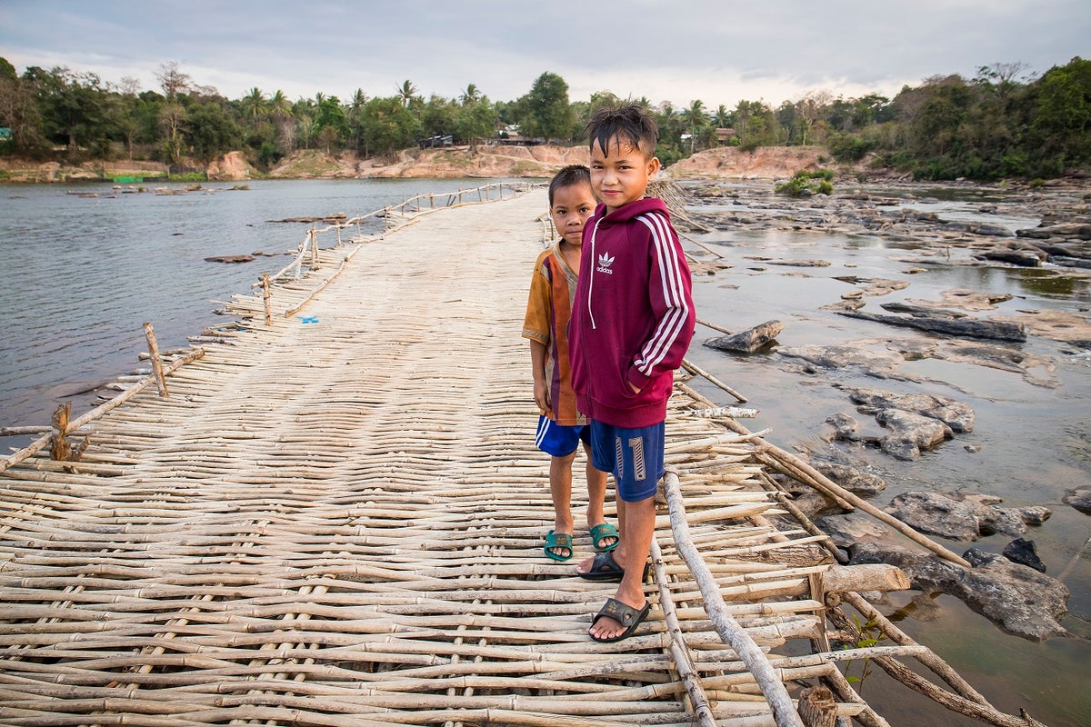 Two children standing on a bamboo bridge.