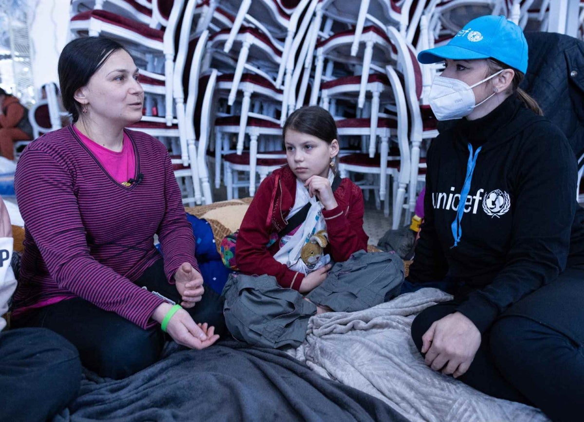 UNICEF worker sits with mother and daughter