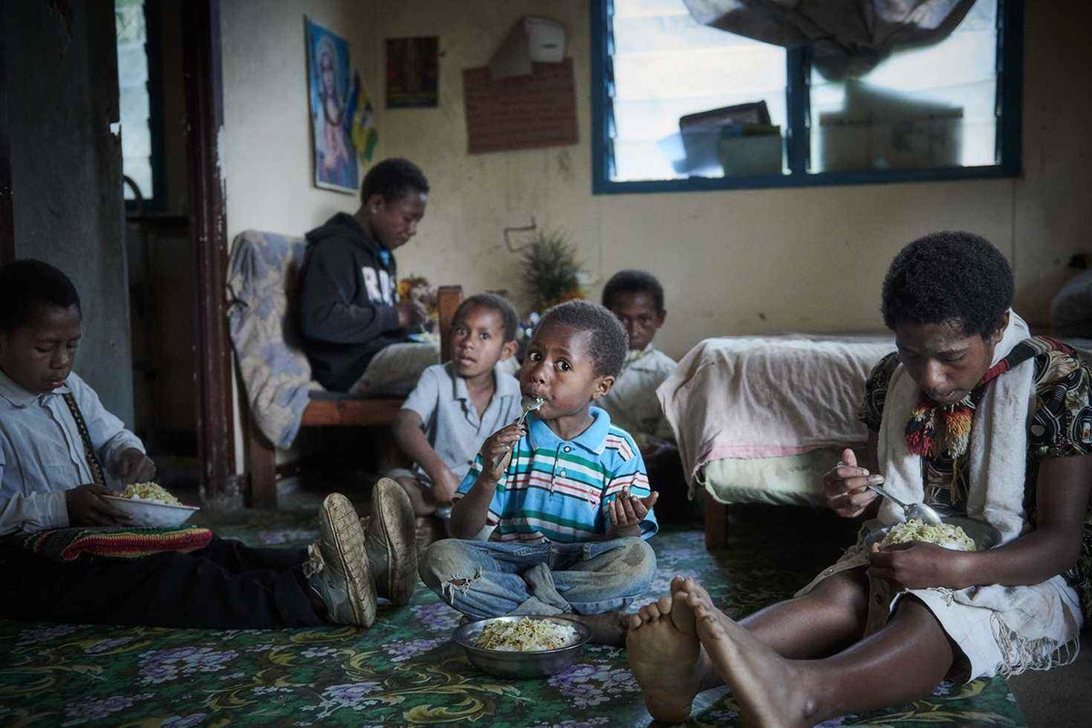 Nick, 4, eats breakfast alongside his siblings at their home in Goglme, Chimbu.