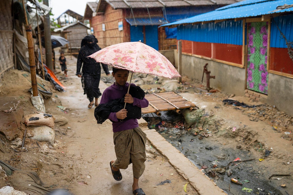 A young boy carries his baby sister through heavy rain.