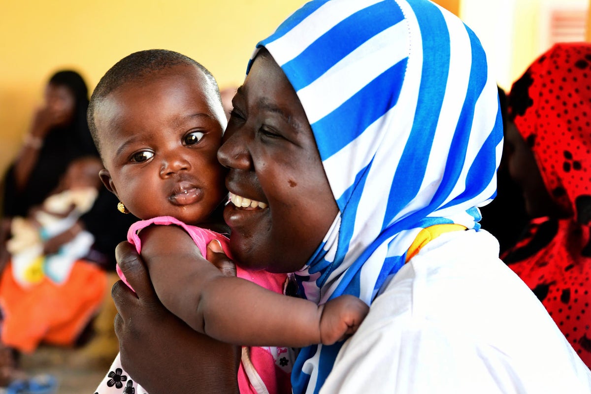 A woman cuddles her baby before being vaccinated.