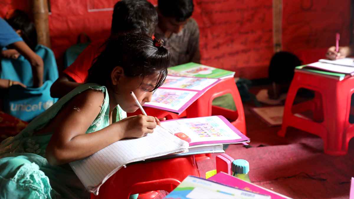A young girl writes in her notebook at a UNICEF-supported learning centre