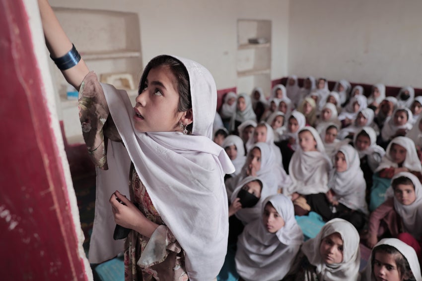 Girl writing on board in class