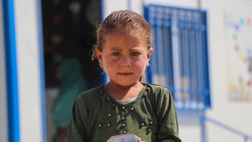 A four-year-old Syrian girl, Soundos, stands outside a UNICEF-supported early childhood center in Syria.