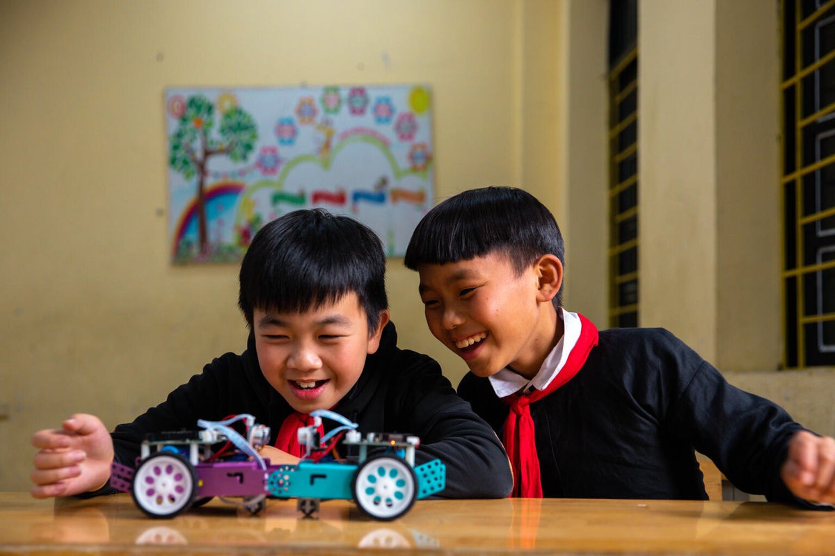 Two Vietnamese boys playing with a robot car during a STEM lesson.