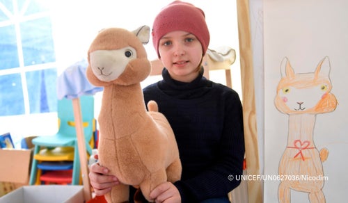 In Romania, 2022, 11-year-old Ukrainian Anastasia poses for a photograph with her new toy while in the UNICEF-supported Blue Dot centre, where her and her family receive emergency support after escaping escalating violence. © UNICEF/UN0627036/Nicodim 