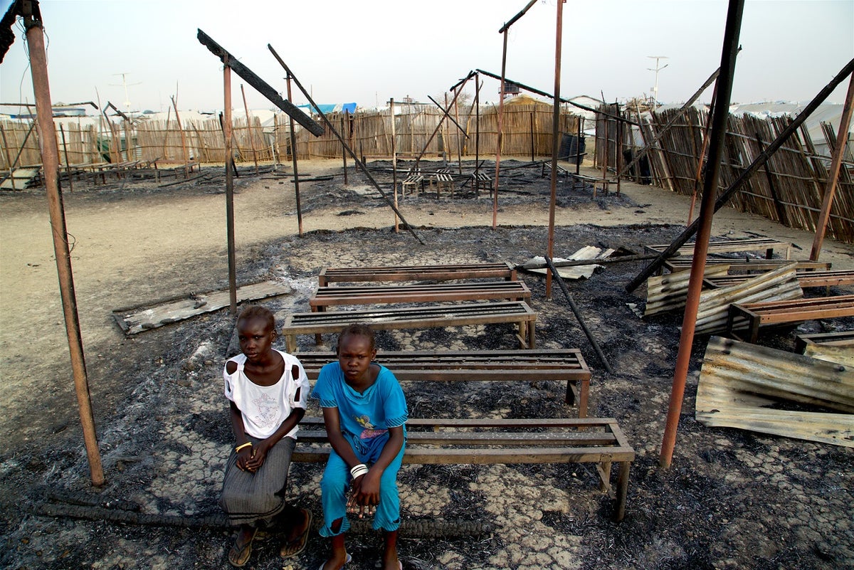 Two children seating on a burnt down classroom.