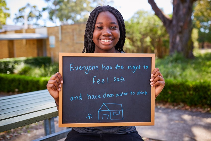 A high school student holding a sign that reads, 'Everybody has the right to feel safe.'