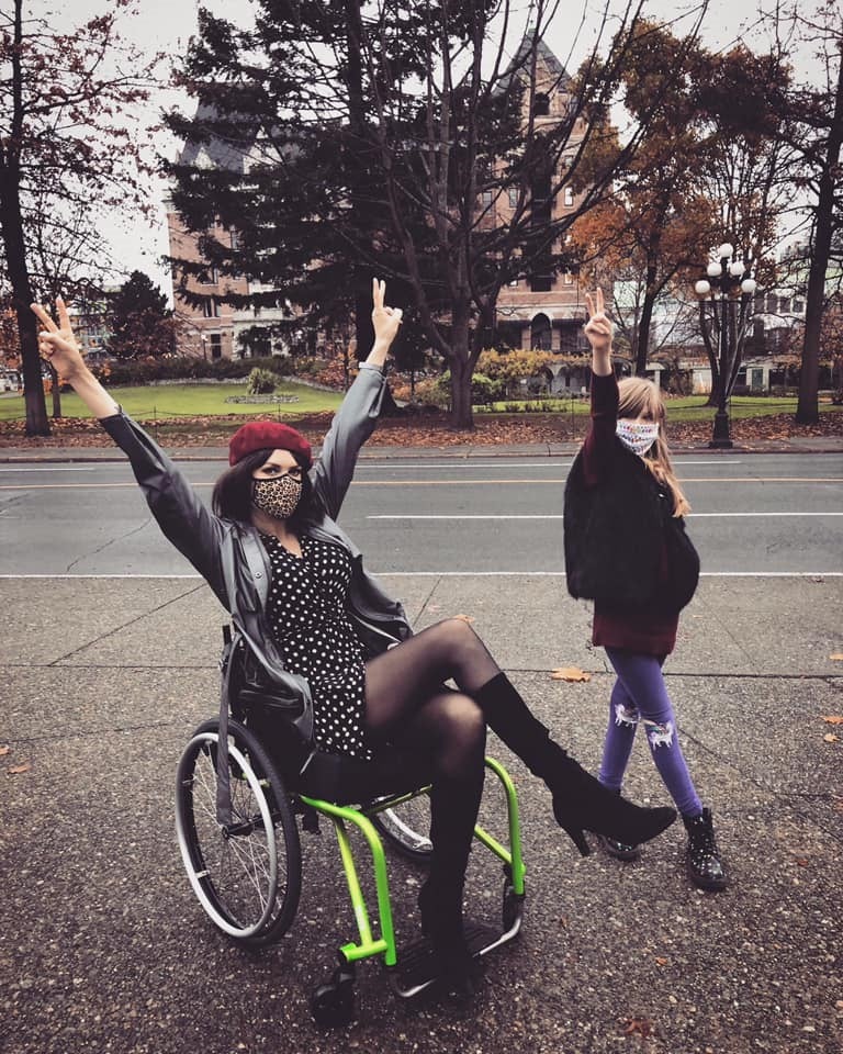 Tara Moss in wheelchair, and daughter with their hands in the air.