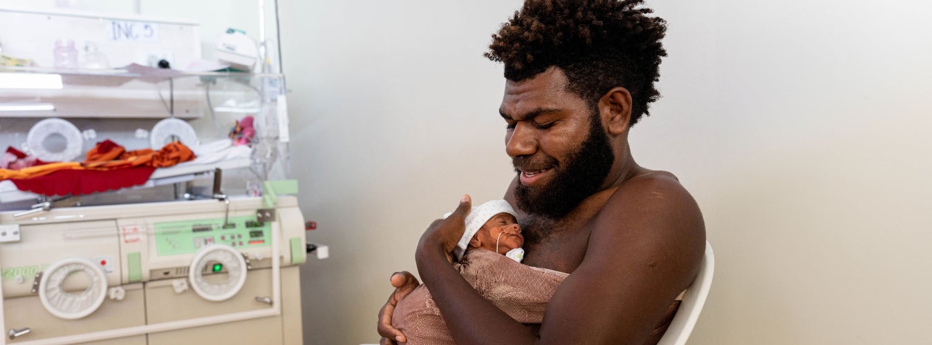 A father holding his newborn against his chest. 
