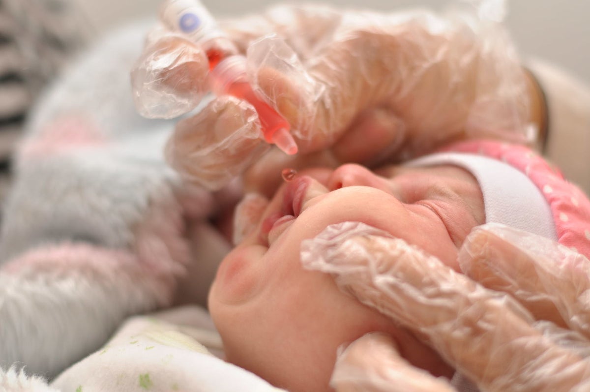 A newborn baby is given a droplet vaccine.