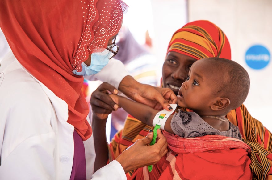 At a camp for internally displaced persons in Ethiopia, where thousands of drought-affected people are staying, a health worker measures the arm of a child to assess him for malnutrition. 