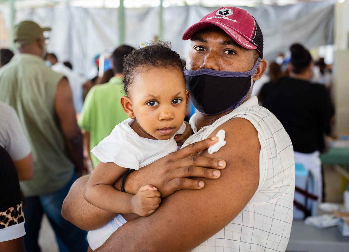 Father after his COVID-19 vaccine, holds his daughter in Haiti.