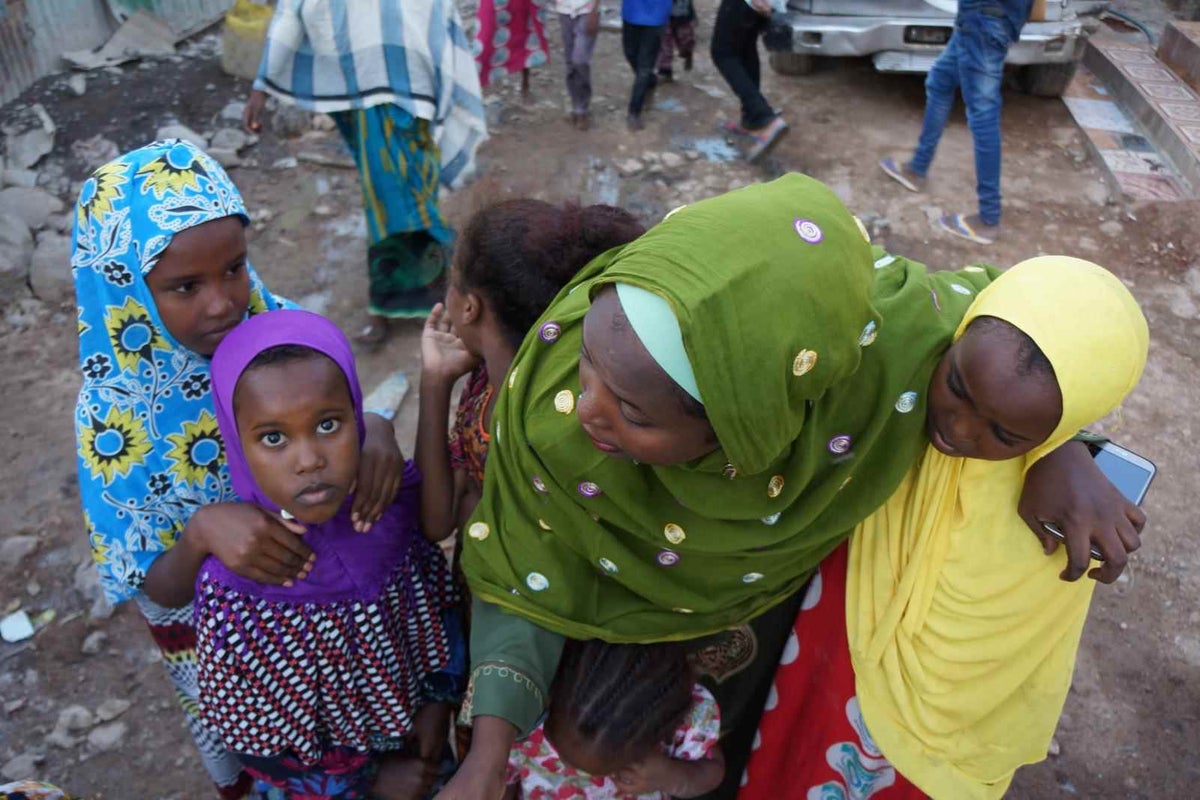 Mariam gathering her girls just outside her home.