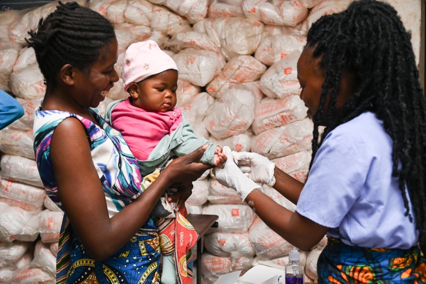 Chifuniro, a 35-year-old flood survivor, watches as her six month old baby tests for Malaria at a school camp in Malawi.