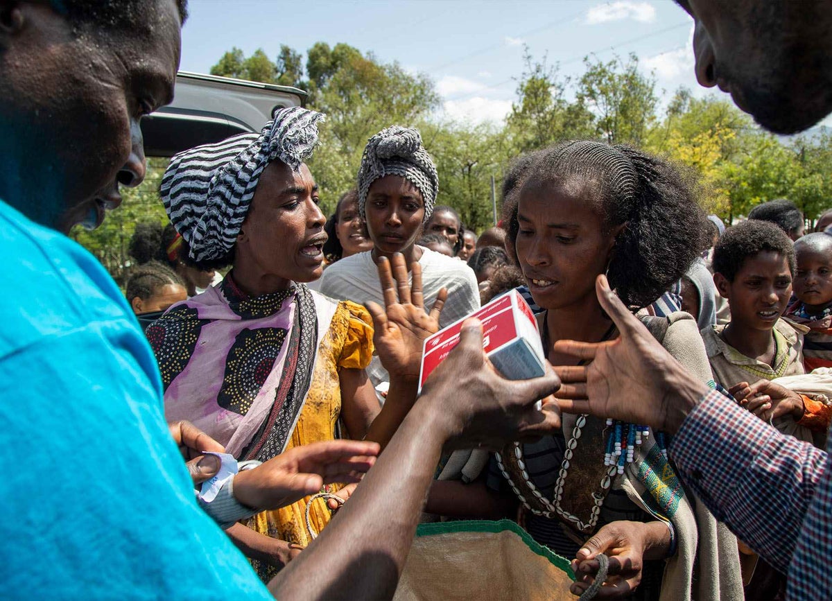 UNICEF Nutrition Specialist and Emergency Response Team member Joseph Senesie (in blue) provides emergency food supplies for severely malnourished mother and children in Tigray, Ethiopia
