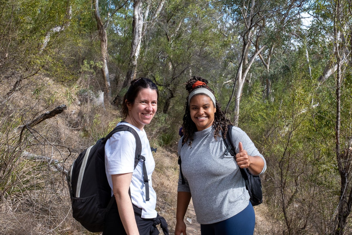 Two women surrounded by trees smiling at the camera