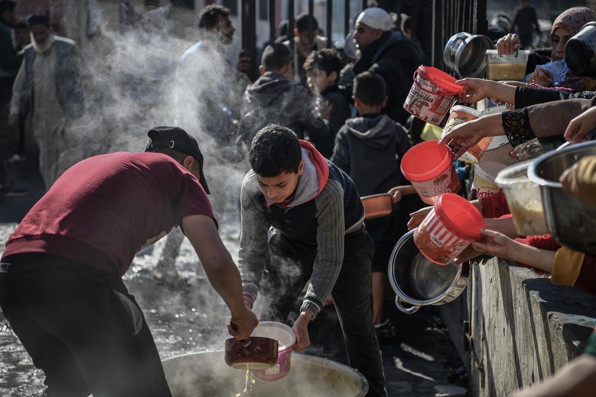 People, including children, wait in a long line to receive a small amount of food in the Gaza Strip.