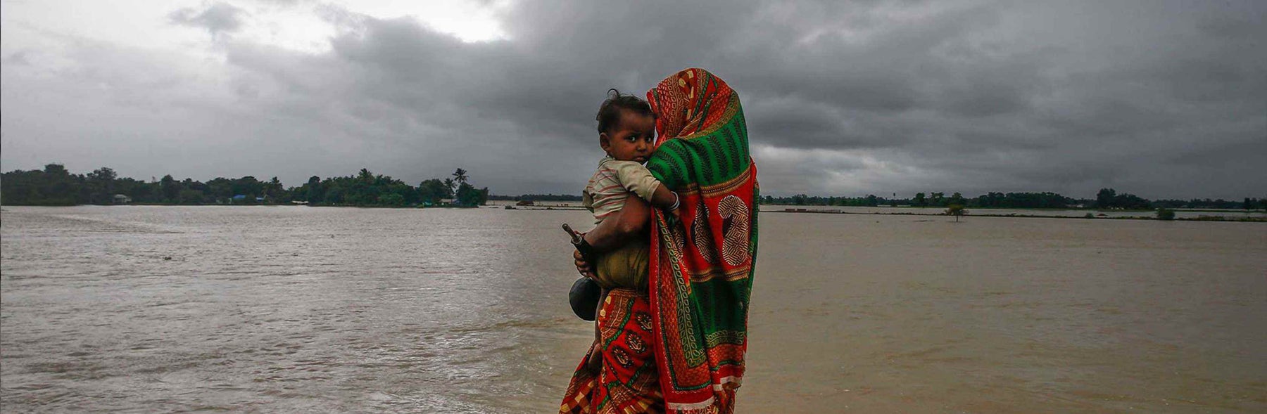 A woman is holding a child in a flooded area