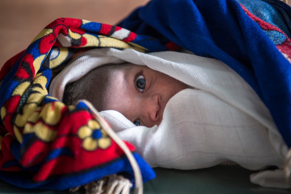 A close up of a very young baby covered in rugs.