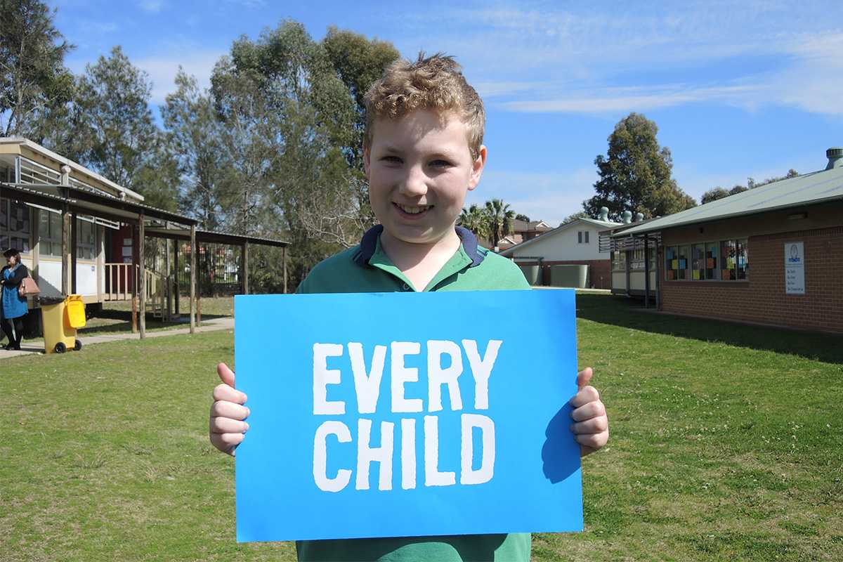 Benjamin holds a sign saying "Every Child"