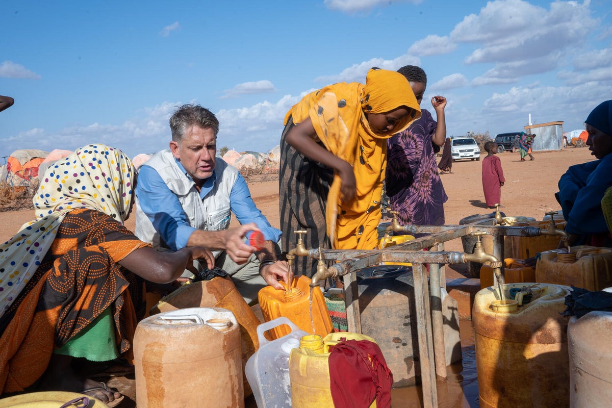 James Elder, UNICEF’s Global spokesperson talks with families who are collecting clean water from a UNICEF supported water pump system in a camp for internally displaced people in Somalia.
