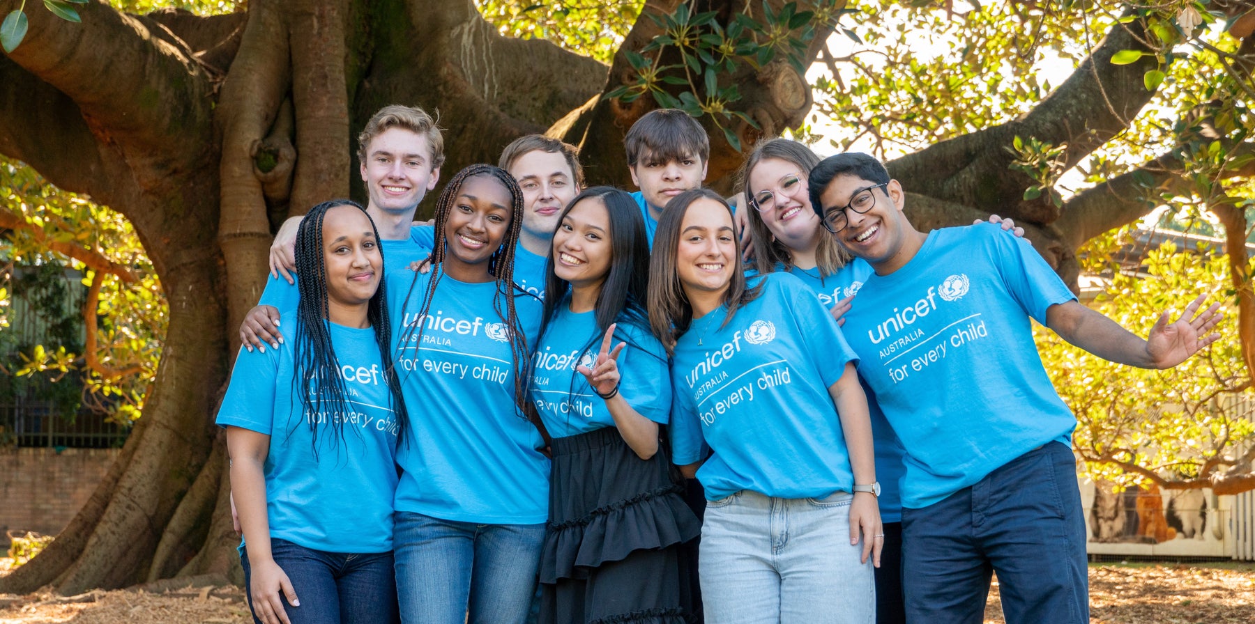 A group of nine young people wearing UNICEF t-shirts and smiling to the camera.
