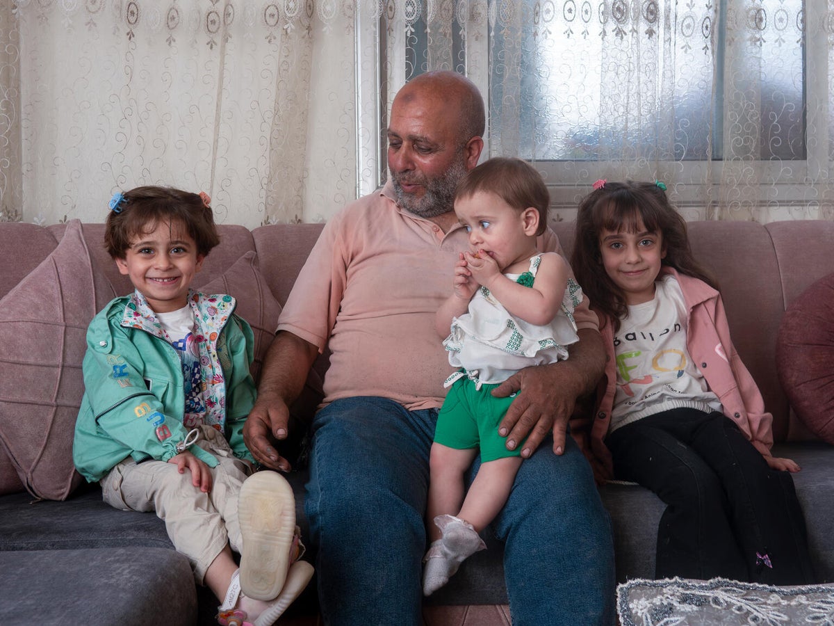 A man with his young daughters at their home in Syria
