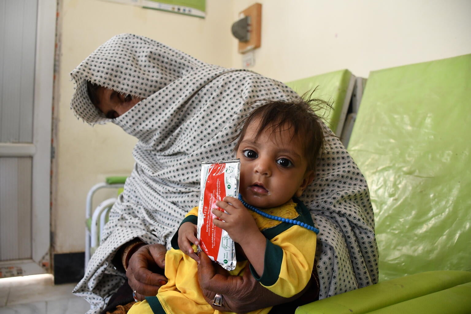 A baby holds a sachet of therapeutic food on their hand