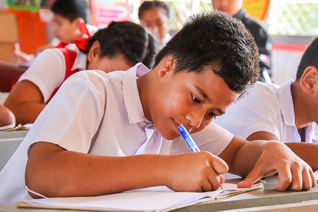 A Tongan boy doing his schoolwork in the classroom.