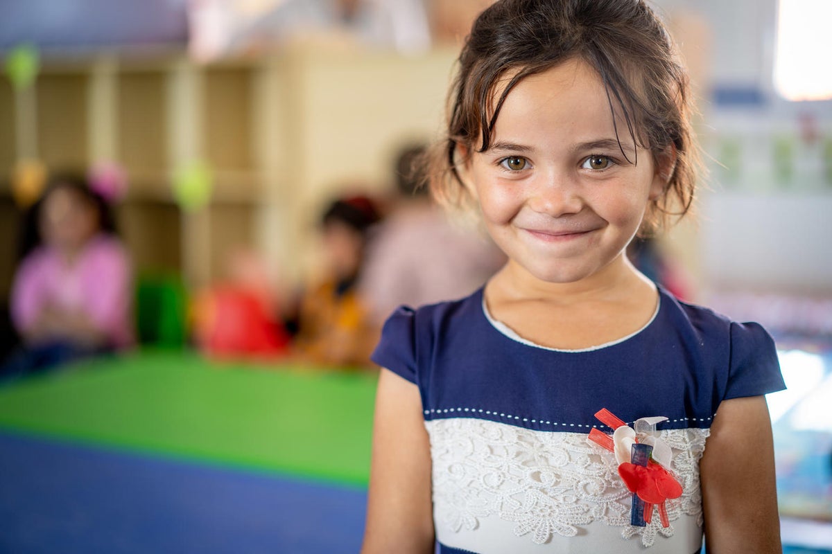 A young girl looks at the camera with a cheeky smile.