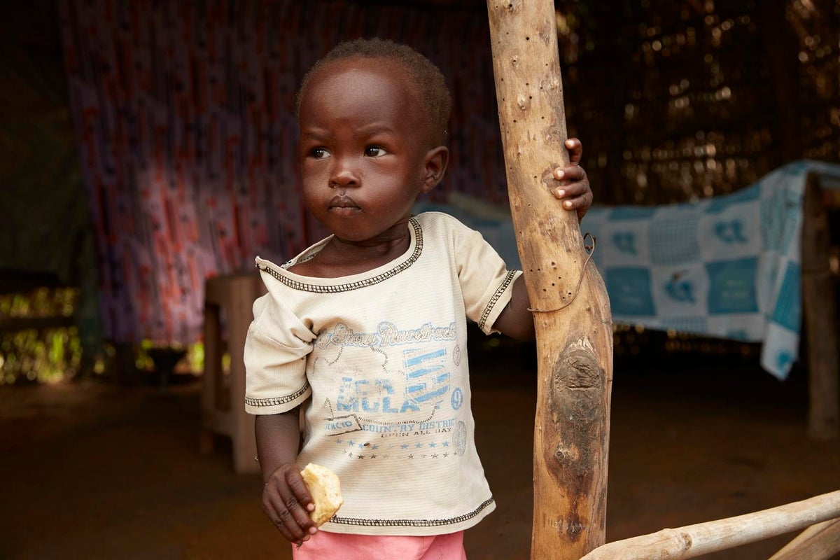 A toddler stands in front of the camera. She looks sad.