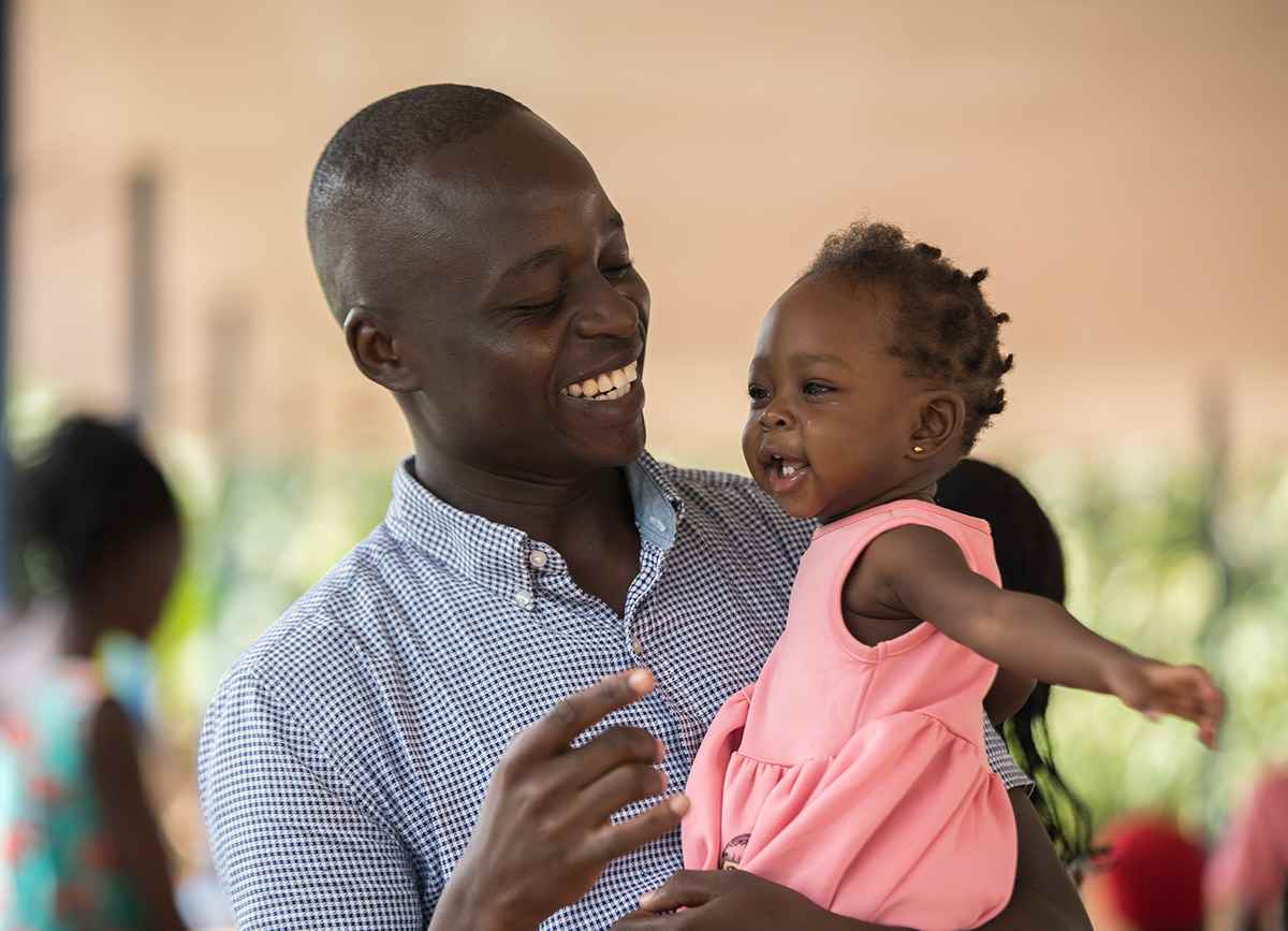 One-year-old Donatel smiles in her father's arms at a health centre in Uganda.