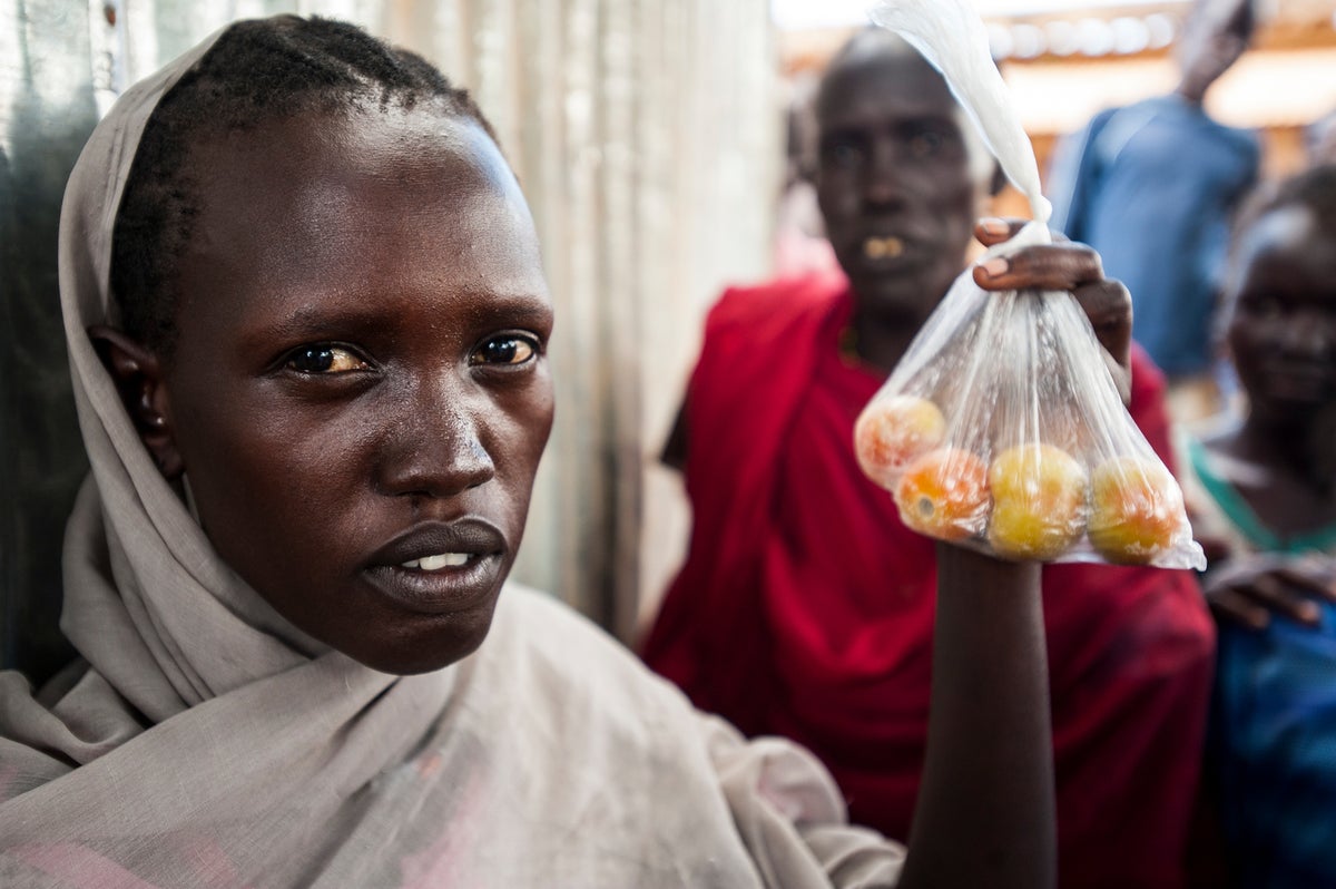 Female face and bag of tomatoes at market