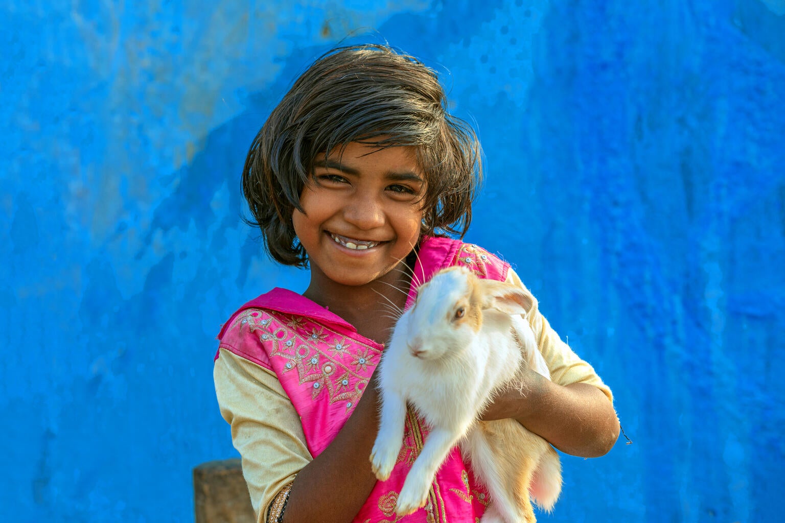 A young girl is holding a rabbit and smiling
