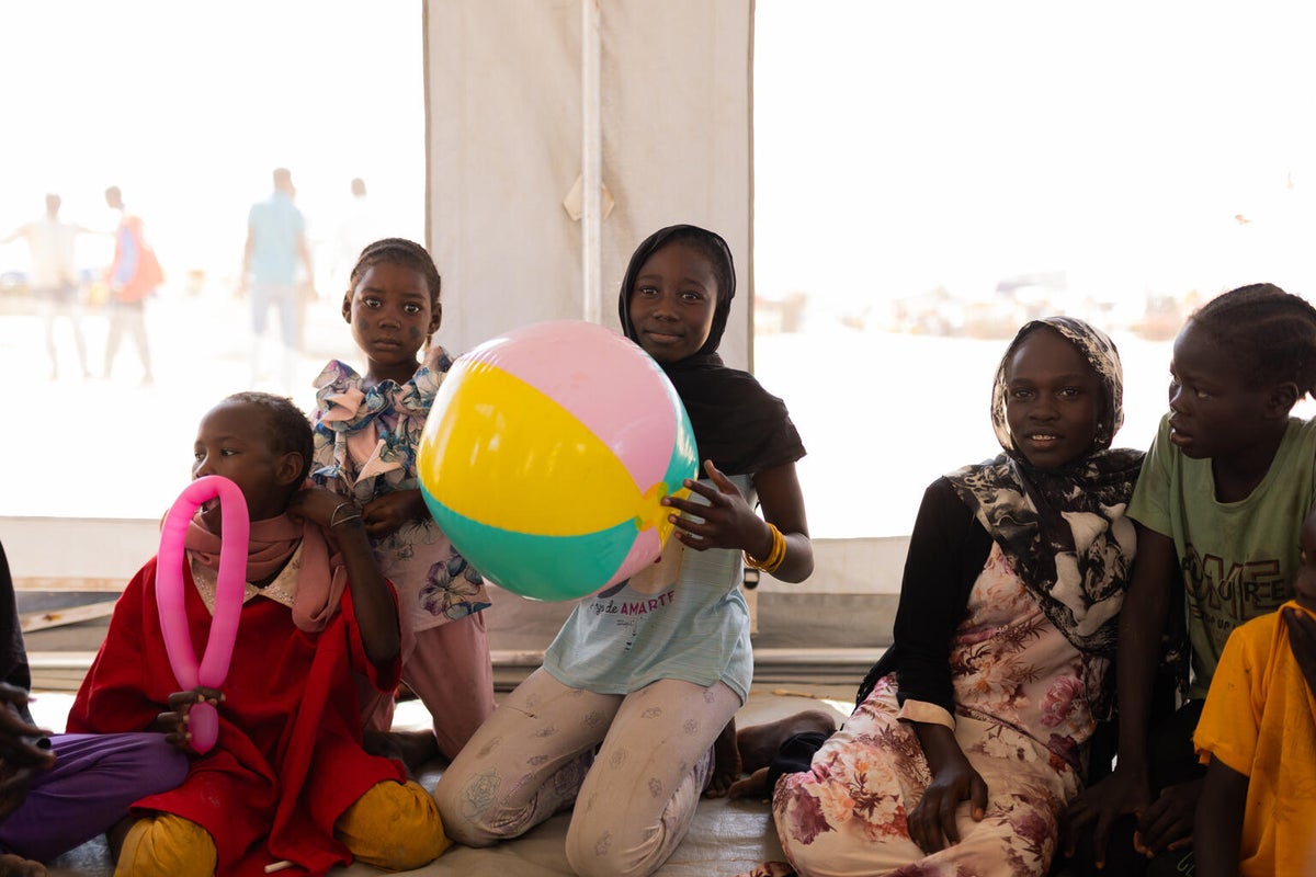 13-year-old Nada holds an inflatable ball as she sits among a group of children at the child-friendly space established by UNICEF in Sudan.