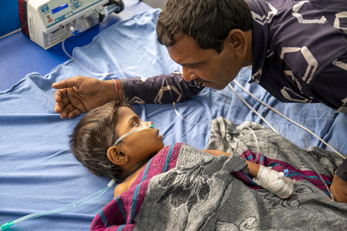 Baby in hospital bed with father looking over them.