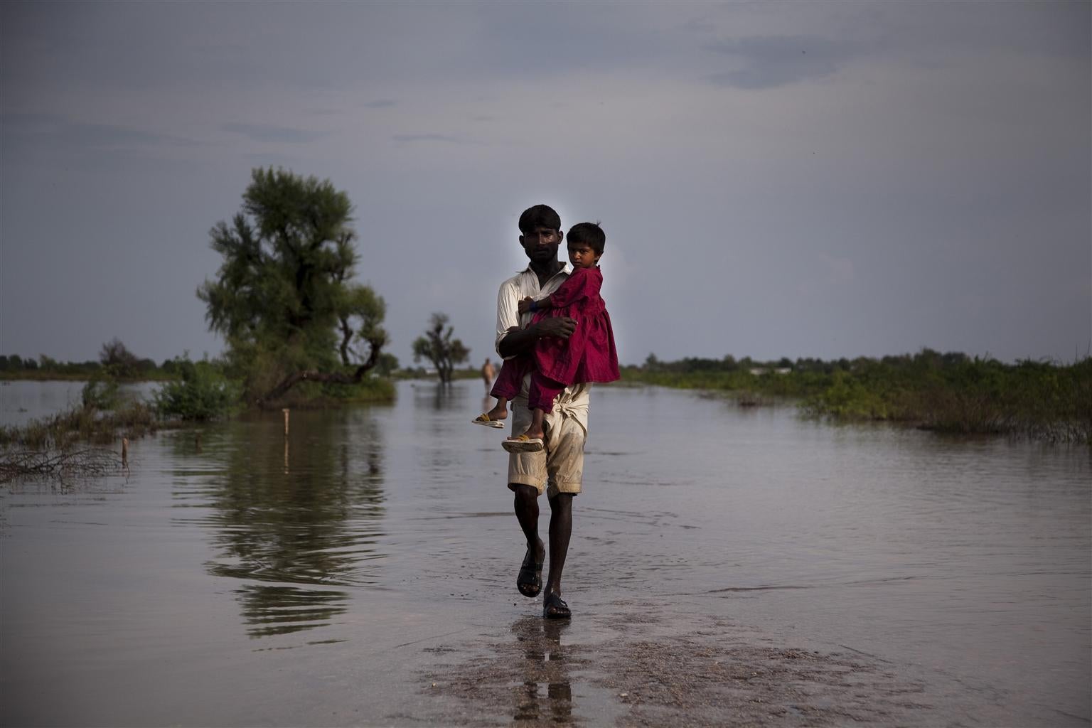 A man carries a child through the flood waters, on 11 September, 2011, in Digri, Pakistan.