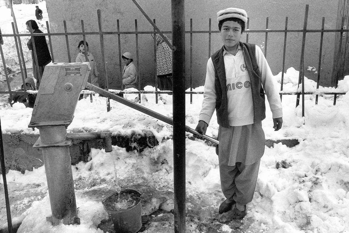 A young boy wearing a UNICEF t-shirt pumps water at his community water pipe in Kabul, in 2000.