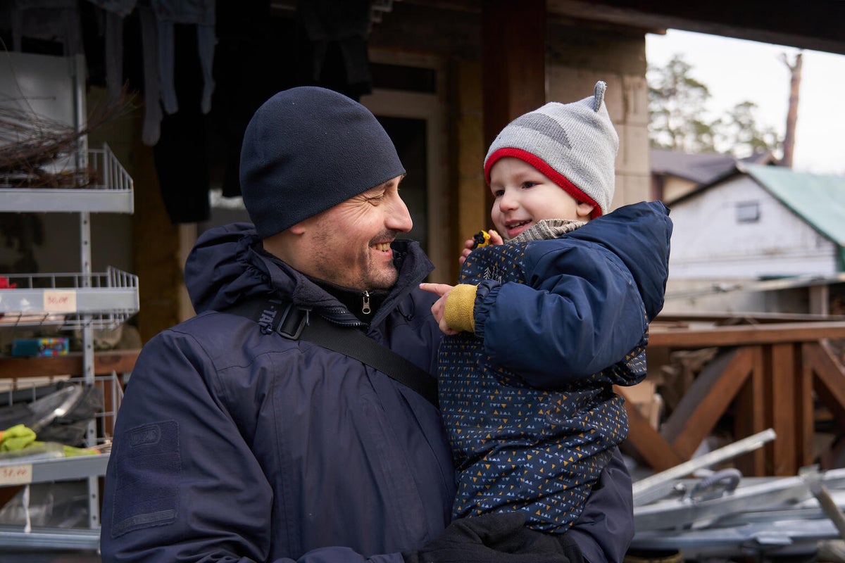 Father holding his son outside their destroyed home in Ukraine