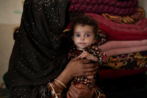 A baby is held in the arms of a woman with a full burqa
