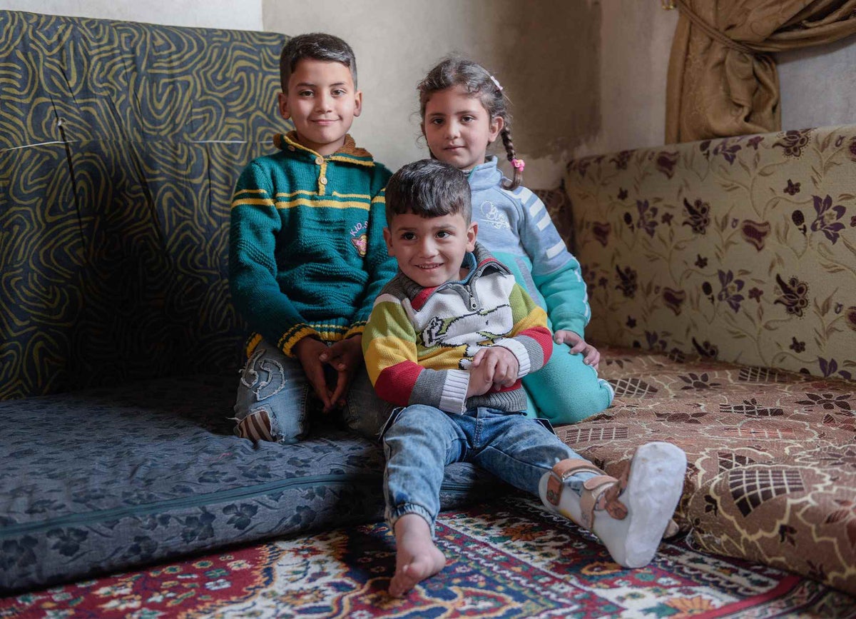 Anwar, Nada and Mohammed pose for a photo in their one room home in Erbin, Syria