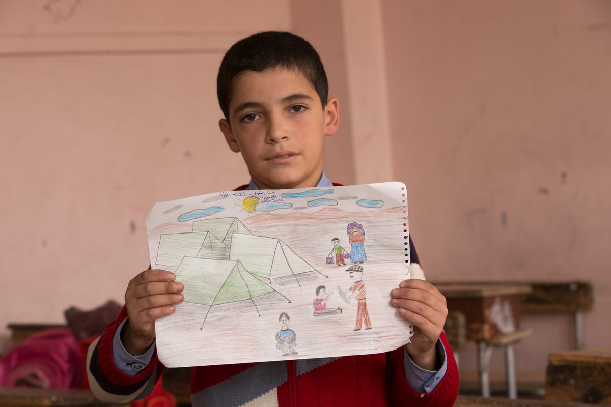 Hassan holds up a picture of a Syrian refugee camp he drew